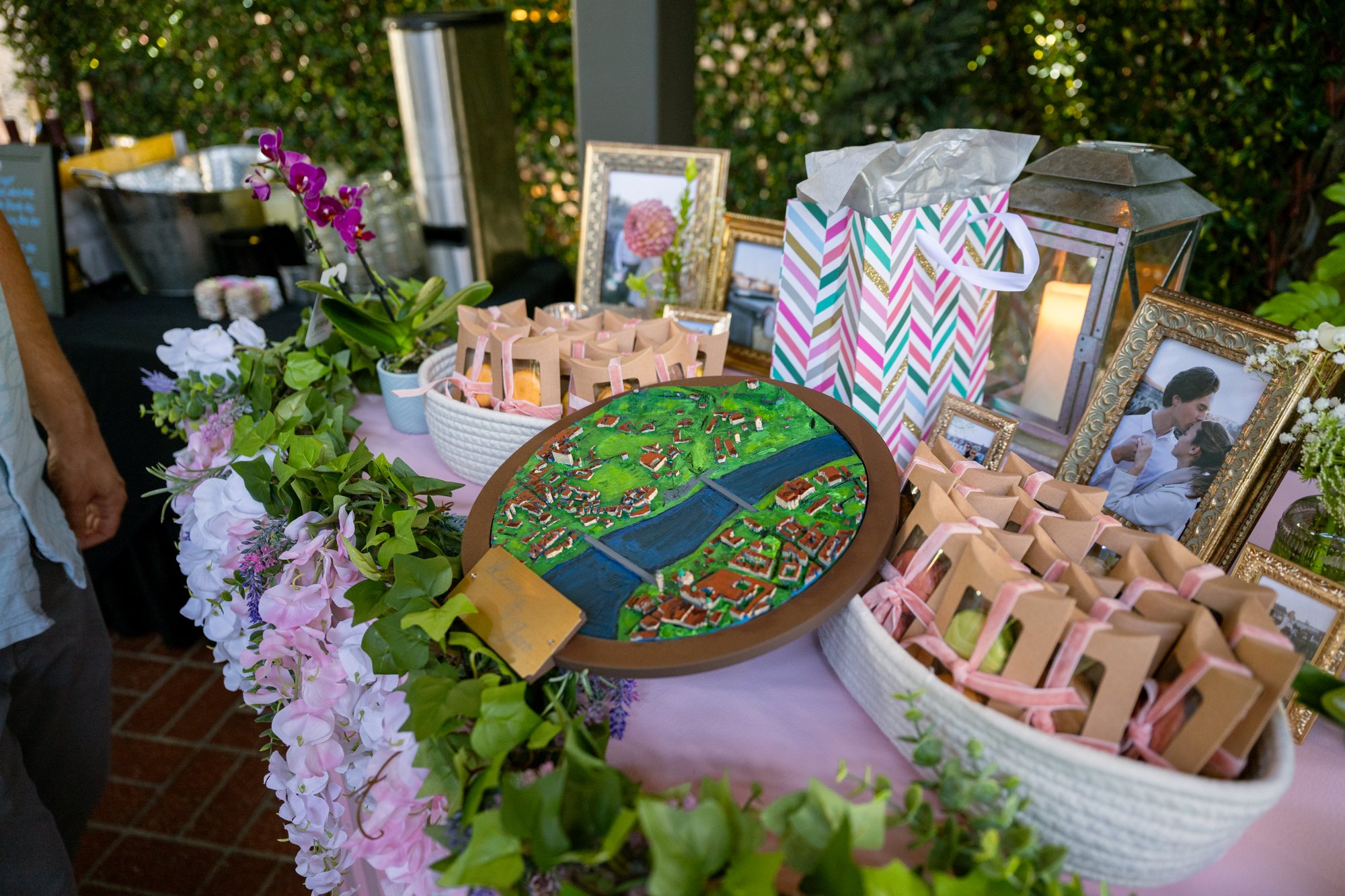 Flowers, favors, framed engagement portraits, and a hand-painted map fill the welcome table.